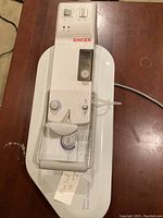 Overall view of the Singer Magic Steam Press showing the device, clear plastic guard, and control panel with dials and buttons.