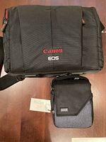 Top view of Canon EOS camera bag and Think Tank smaller accessory bag on wood floor.