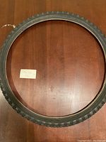 Top-down view of new black bicycle tire sized 26 x 1.95 on a wooden surface.