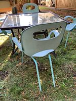 One light blue plastic chair seen from back showing design with large cut-out handle and curved armrests, on grass.