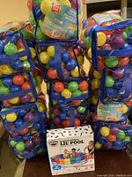 Photo showing thirteen bags of colored plastic balls surrounding a boxed Magical Rainbow Lil' Pool.
