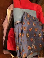 Box with assorted folded fabrics including red flannel, blue printed cotton fabric, and others