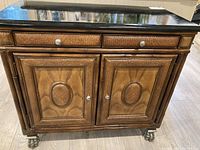 Front view of the Ernest Hemingway Collection rattan side cabinet showing two drawers and two cabinet doors with black marble look top.