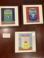 Three framed Studio Ghibli themed soup can prints with brown frames and slight vintage marks.