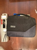 Mini tripod in packaging next to closed black and grey Think Tank camera bag.