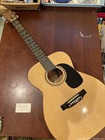 Full top view of the vintage Marlin acoustic guitar on a wooden table, showing the body, fretboard, and headstock.