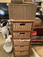 Wooden stand with 5 wicker drawers and cutout handles, fabric liners visible on some baskets