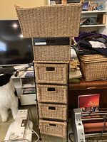 Front view of the tall wicker stand with five removable wicker bins and a black metal frame, shown in a room setting