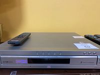 Front view of Sony 5-disc DVD/CD player with remote placed on top, showing power button and disc control buttons, labels for DTS and Dolby Digital.