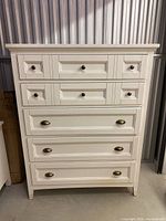 Front view of white dresser chest showing drawer configuration and hardware