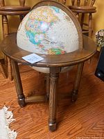 View of the globe showing the North and Central American continents with the wooden stand and part of surrounding furniture.