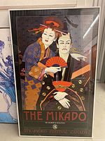 Full view of framed print titled 'The Mikado' showing two traditional Japanese figures in colorful attire holding fans and umbrella.