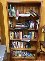 Frontal view of the pine wooden bookcase filled with various books and papers to show size and shelving.