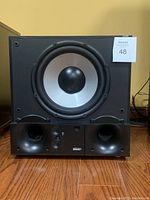 Front view of Energy S10 Subwoofer showing silver cone, black surround, ports, and controls with Energy logo.