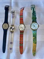 Four ladies Swatch watches laid flat showing full band designs and dial faces from a distance.