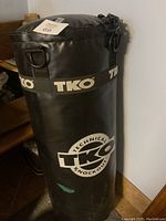Full view of the TKO punching bag showing cylindrical shape, black synthetic surface and logo.