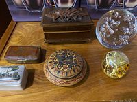 Photo of all items on wooden surface including trinket boxes, music box, and paperweights