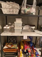 Shelf view of assorted aluminum baking trays, plastic pantry containers, small containers, metal baking pans, and foil/wrap products in packaging.