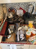Overall view of baking items including hand mixer, stainless steel bowls, sifter, candles, and kitchen tools arranged on counter.