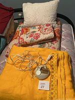 Full/Queen floral quilt with matching pillow cases and one white textured pillow on bed along with vintage yellow Sears electric blanket and control unit in foreground