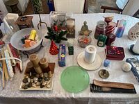 Wide view of the table showing many different candles, candle holders, votive candles, decorative stones, and small Christmas decor