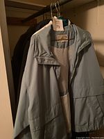 Light blue ladies coat hanging on a hanger showing front and collar with mesh inner lining visible