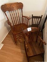Photo showing the three wooden chairs grouped together: one large adult rocking chair, one smaller child rocking chair, and one smaller stationary wooden chair.