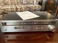 Silver face Lloyd's H655 stereo tuner showing front with analog AM/FM frequency dial, buttons, sliders, and tuning knob.