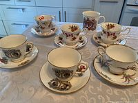 Photo of five Royal Albert Tartan Series teacups with saucers and one Royal Stafford Crown Trent commemorative mug on a table