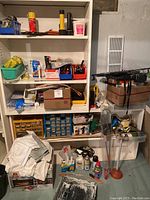 Full view of basement shelving with assorted hand tools, spray cans, pliers, wrenches, polish bottles, toothbrushes, and hardware boxes.
