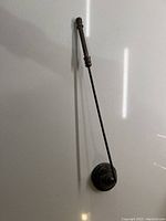 Full view of the antique candle snuffer showing the entire length and handle against a white background.