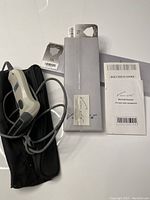 Photo showing barcode scanner, black pouch, original box, and instruction manual arranged on flat surface.