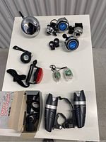 Full view of the collection showing bike bells, front and rear bike lights, and small LED lights on a white surface.