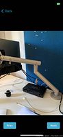 Side view of Herman Miller Flow monitor arm clamped to desk holding the monitor; cables and audio interface on desk