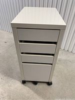 Front view of closed white IKEA Micke rolling drawer unit on castors.