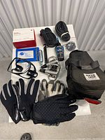 Photo showing all items in the lot: 3 boxes of Bontrager tubes, gloves, pedals, bag, lube, CO2 cartridge, bike computer mount, Park Tool tire boot