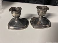 Pair of silver plated candle holders side by side on a flat surface showing their detail and shape