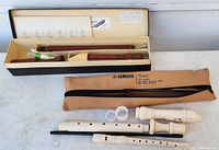 Full view showing Yamaha Tenor Recorder YRT-30B II disassembled in three parts with white ABS plastic body, two small white cylinders, and black cleaning rod, alongside brown zippered carrying bag labeled Yamaha Tenor made in Japan/India.