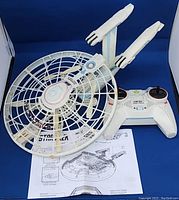 Drone and remote controller on blue backdrop including printed manual.