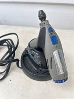 Front view of Dremel Stylus 865 in charging base with visible power cord.