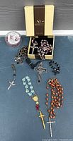 Full lot overview showing all rosaries including boxed Gherelli rosary, and various vintage rosaries with different bead types and crucifixes