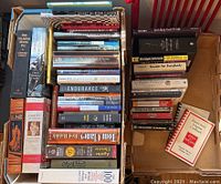 Top-down view of mixed books lot showing a variety of titles in two stacked boxes, including Old Soldiers Never Die, Dune, and Multiple Sclerosis For Dummies.