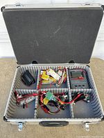 Open carrying case with foam sections containing multiple RC components including batteries, charger, and connectors.