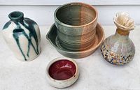 All four pottery pieces shown together on a white surface including planter, two bud vases, and small bowl