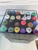 Top view of marker caps showing 24 different colors including shades like Aqua Mint, Cool Gray, Yellow, Violet, Orange, Brown, and Blue.