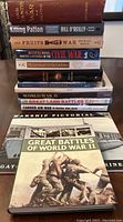 Stack of 11 war-related books showing titles and authors.