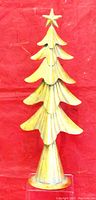 Mini gold painted metal Christmas tree with star topper, 17 inches tall, photographed against red background.