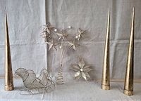 Three tall metal conical decorative cones, wire sled, and metal star topper piece arranged on fabric background