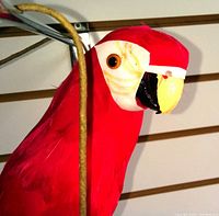 Close-up image of large handmade red parrot figurine showing red feathers and detailed face