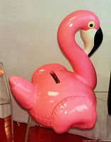 Pink flamingo shaped glossy plastic money bank, approximately 6 inches tall with a slot for coins.